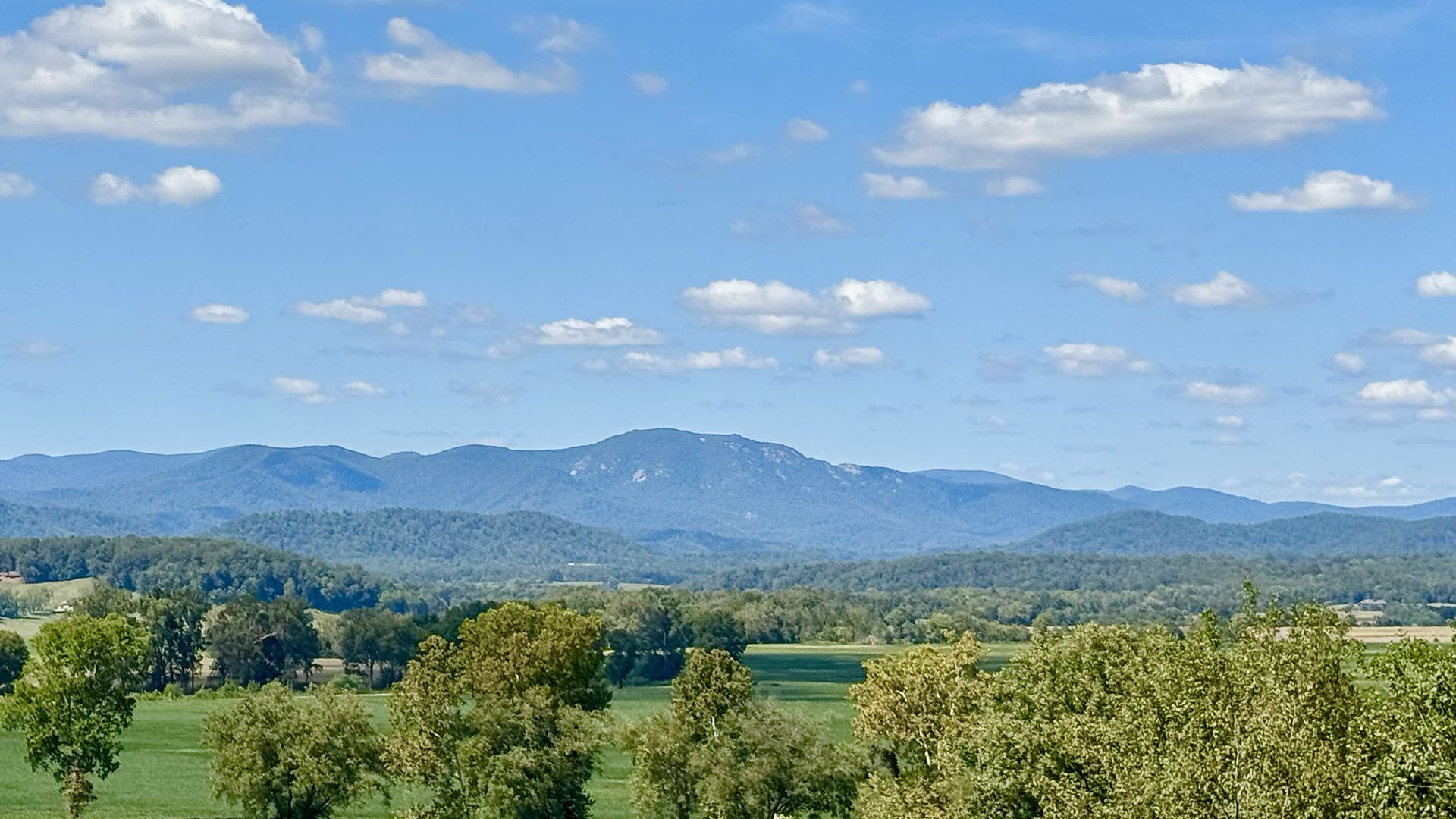 Blue Ridge Mountains under a blue sky with green fields below